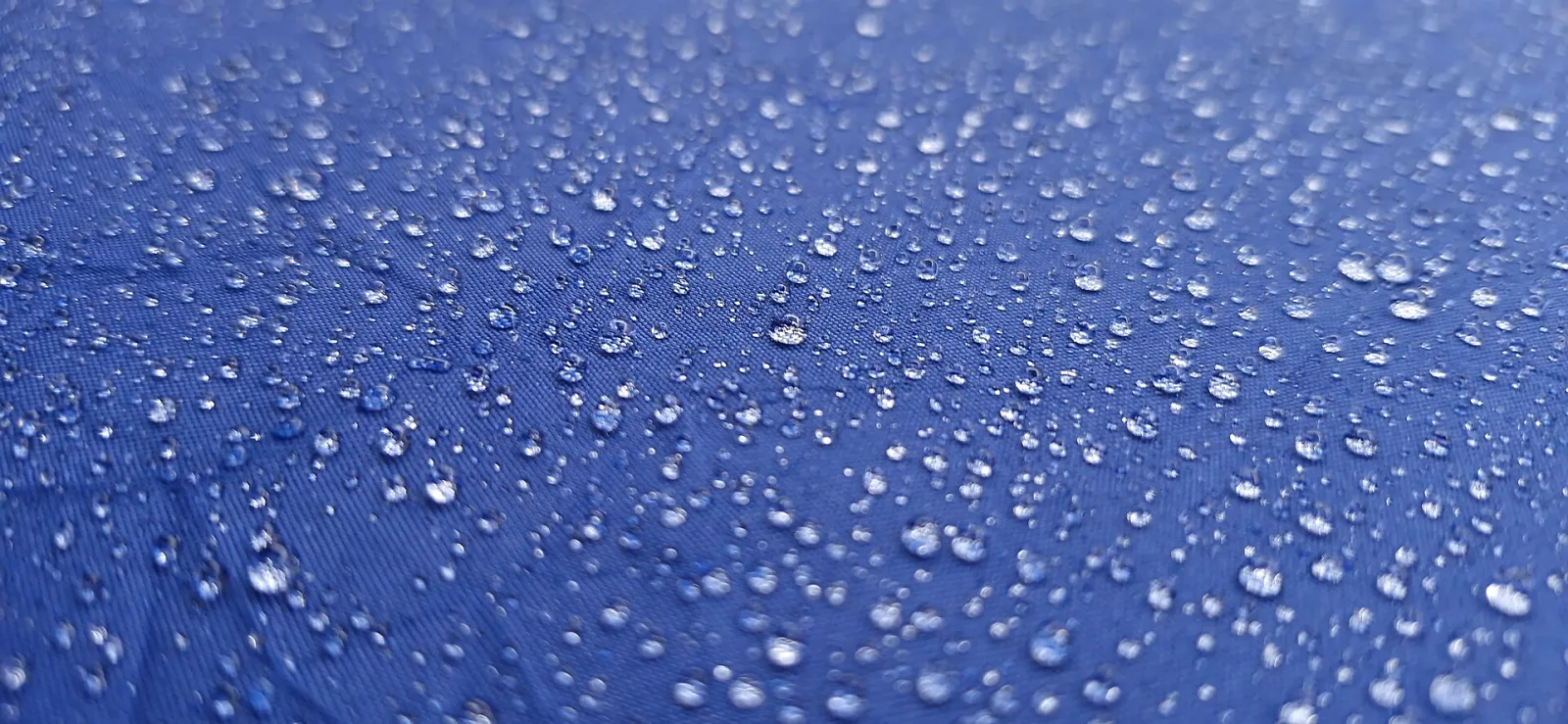 Gotas de lluvia sobre la tela de un paraguas azul.