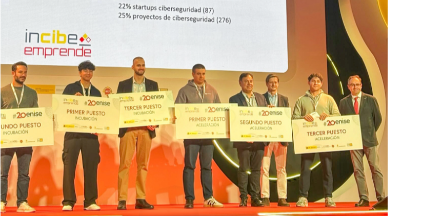 Ocho personas de pie en un escenario sostienen carteles con premios de incubación y aceleración de 20ENISE.