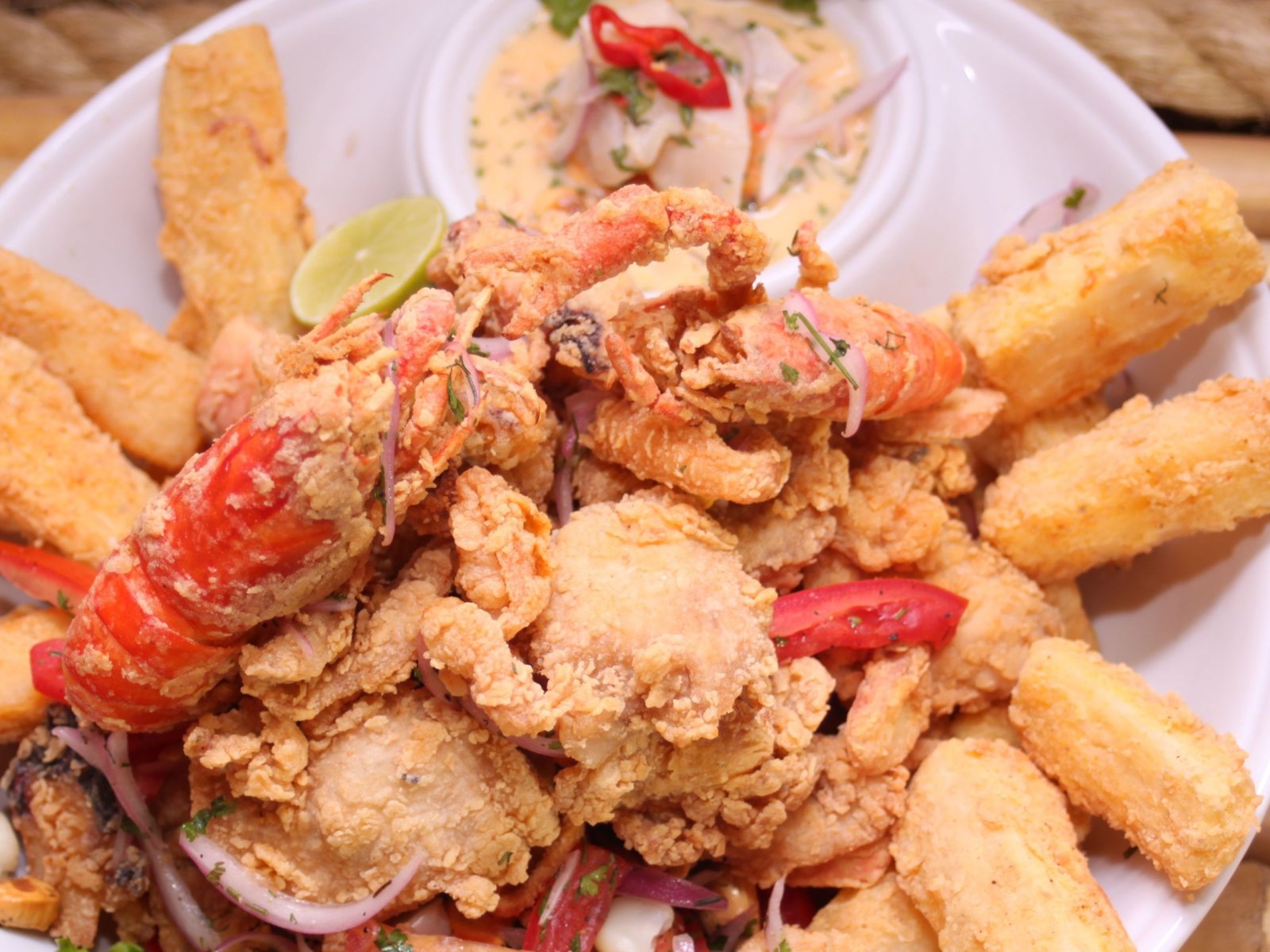 Plato de marisco frito con langostinos, trozos de pescado rebozado, tiras de calamar, cebolla morada y lima.