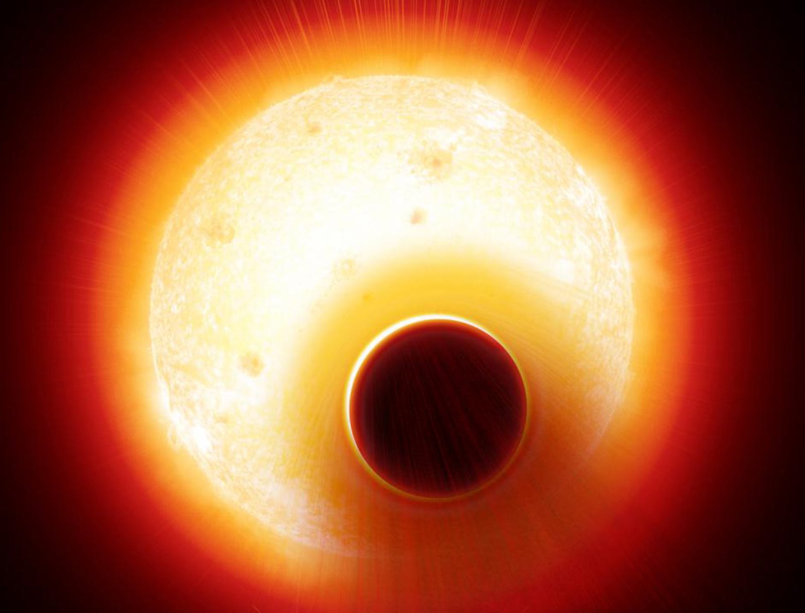 Una gran esfera luminosa amarilla y naranja con manchas oscuras en su superficie y un disco oscuro recortado sobre ella.