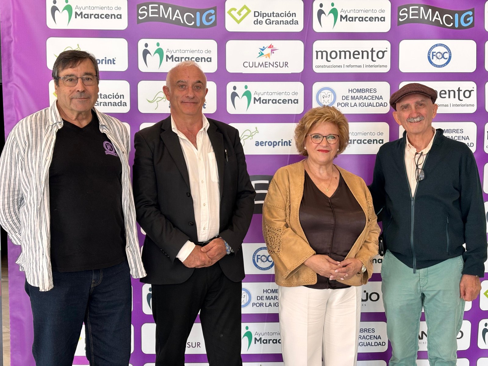 Cuatro personas adultas posan de pie ante un panel morado con logotipos de Maracena, SEMACIG y otras entidades.